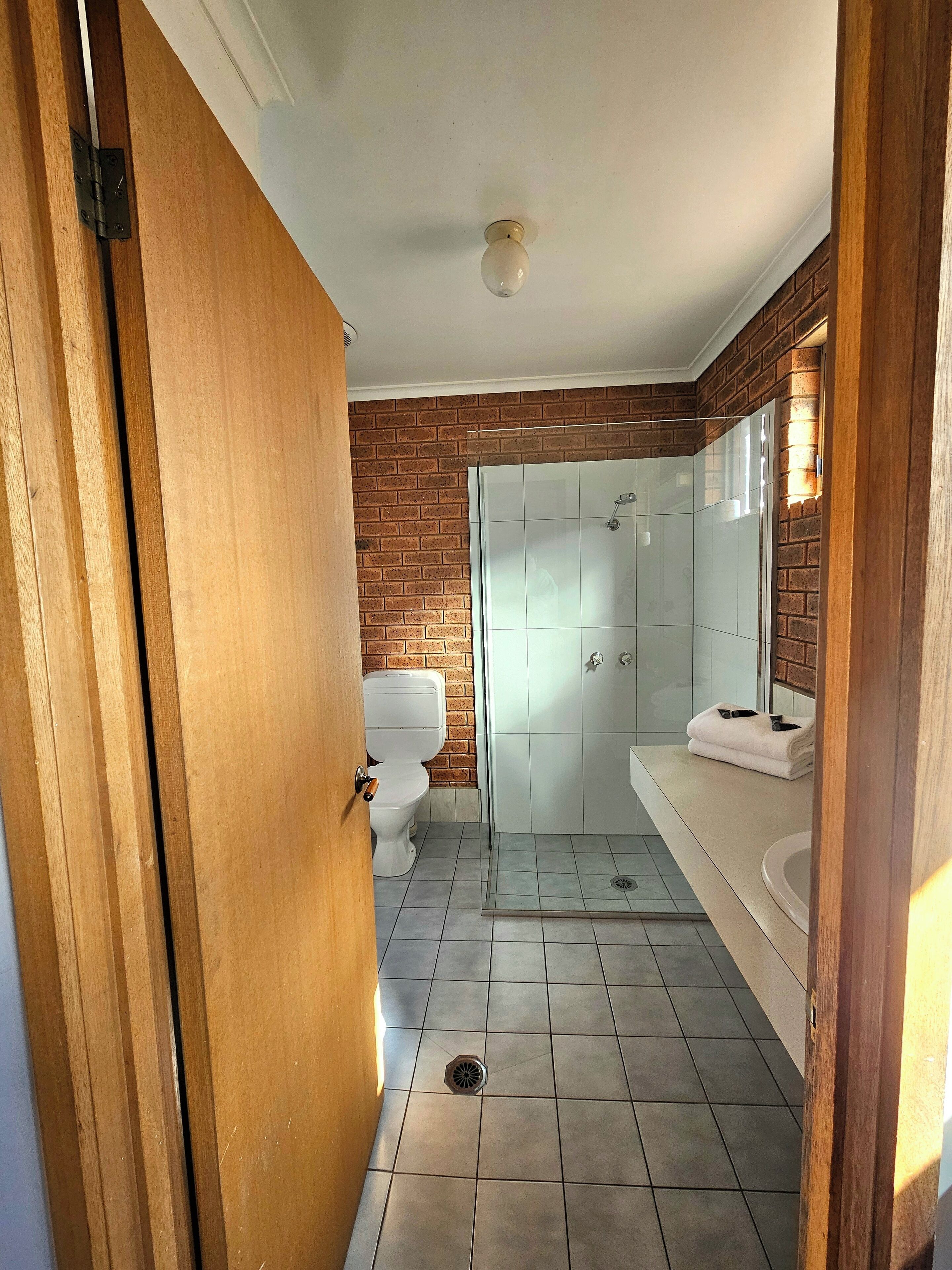Une salle de bain comprenant des toilettes, une douche avec une porte en verre et un lavabo avec une serviette.