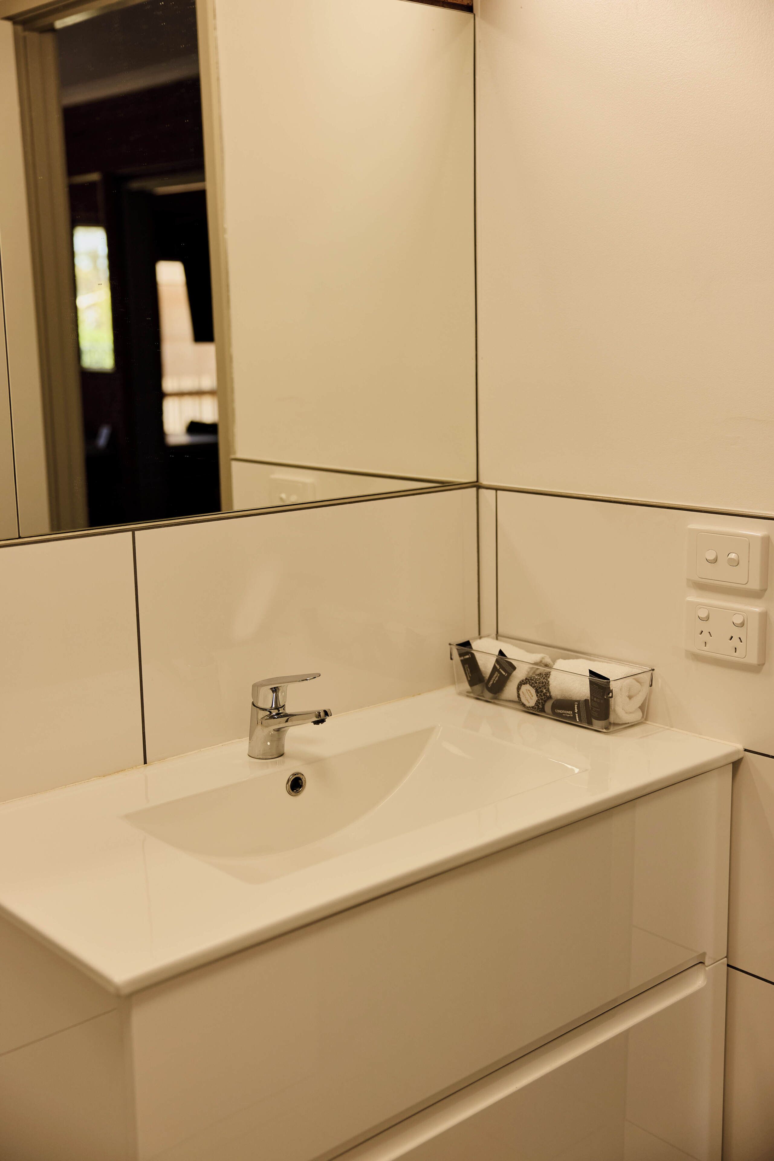 A bathroom with a white sink, mirror, and tiled walls.