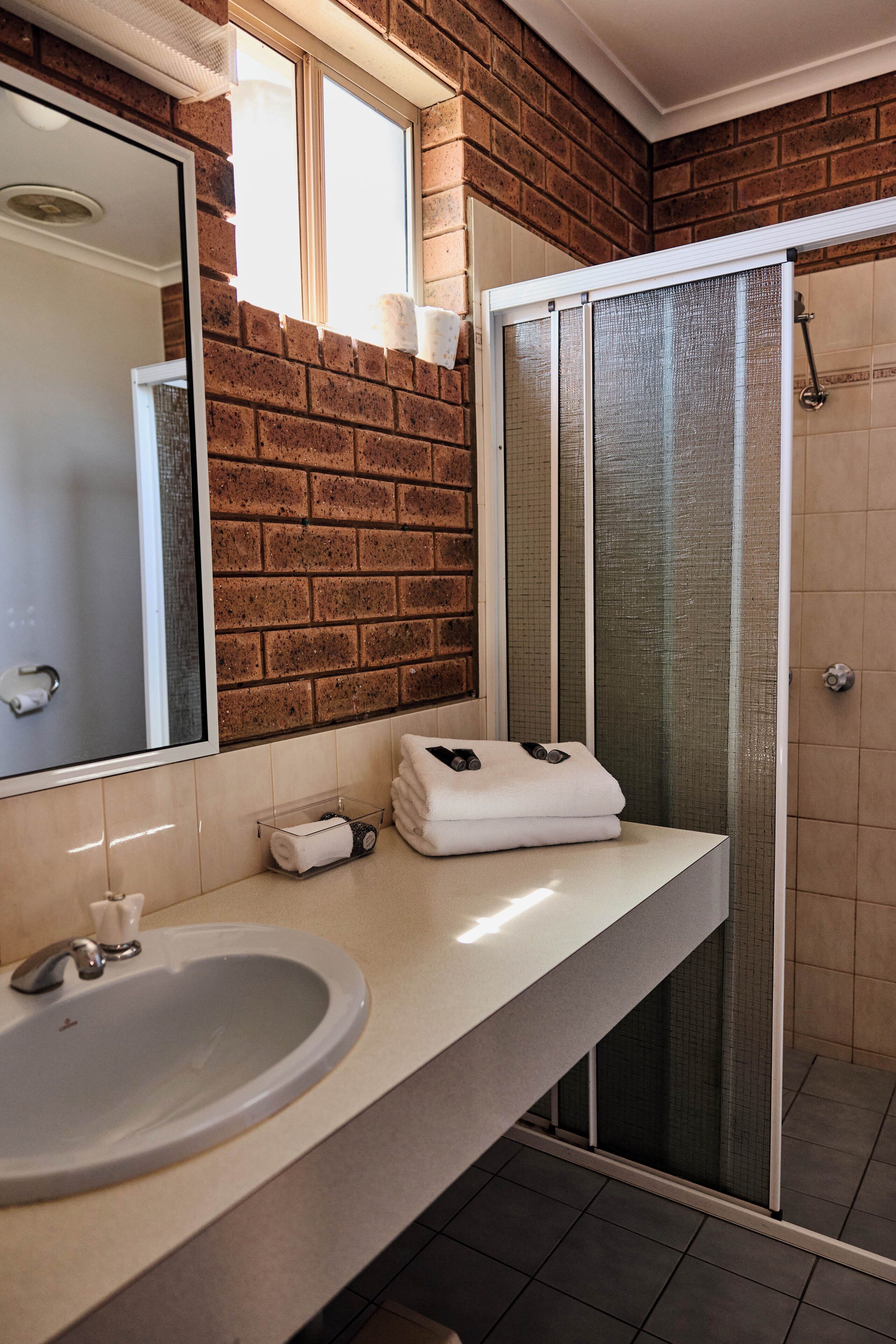 A bathroom with a sink, mirror, towel rack, and a glass shower enclosure.