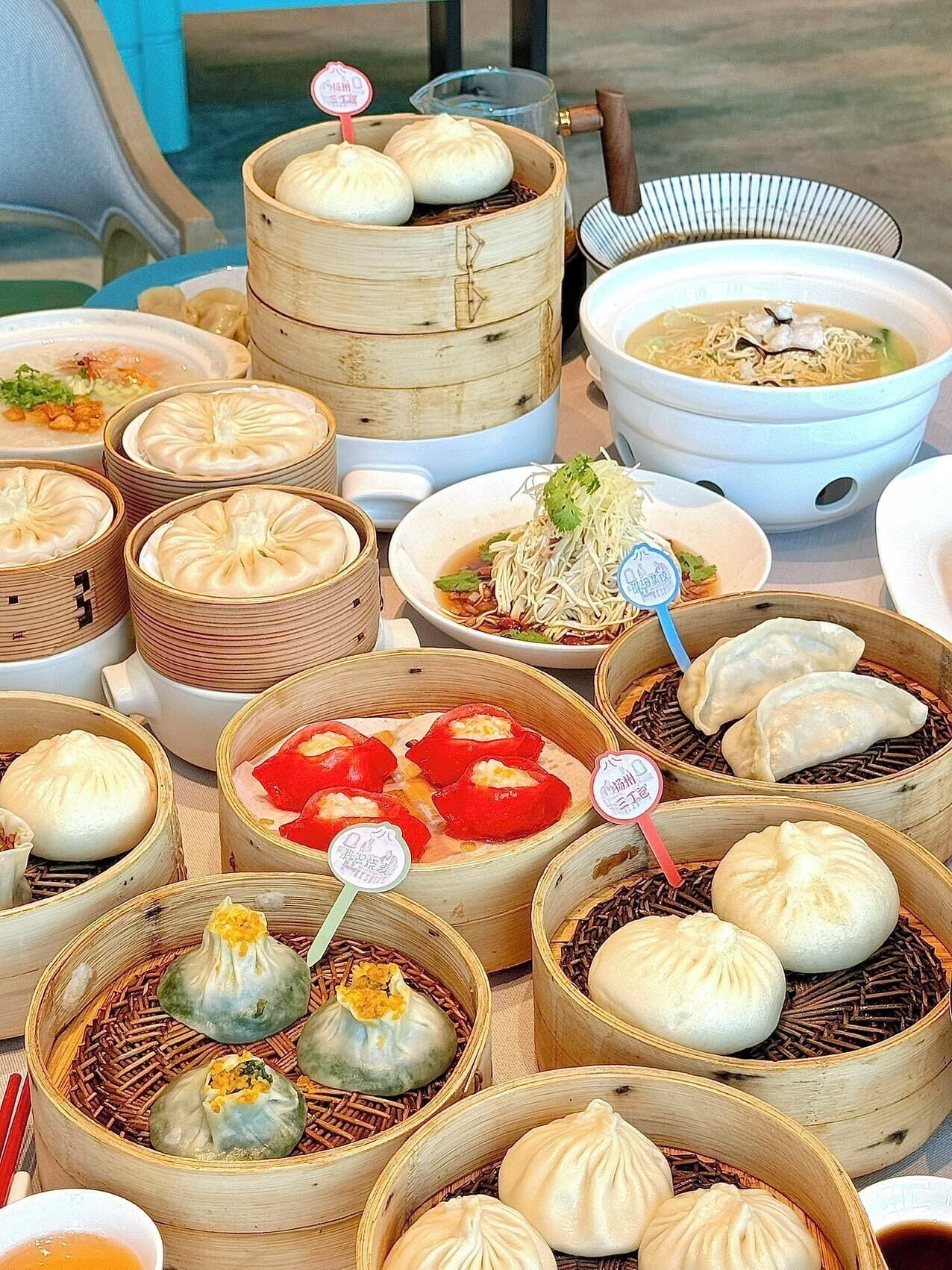 A variety of Asian dishes, including dumplings and noodle soup, served in bamboo steamers and bowls.