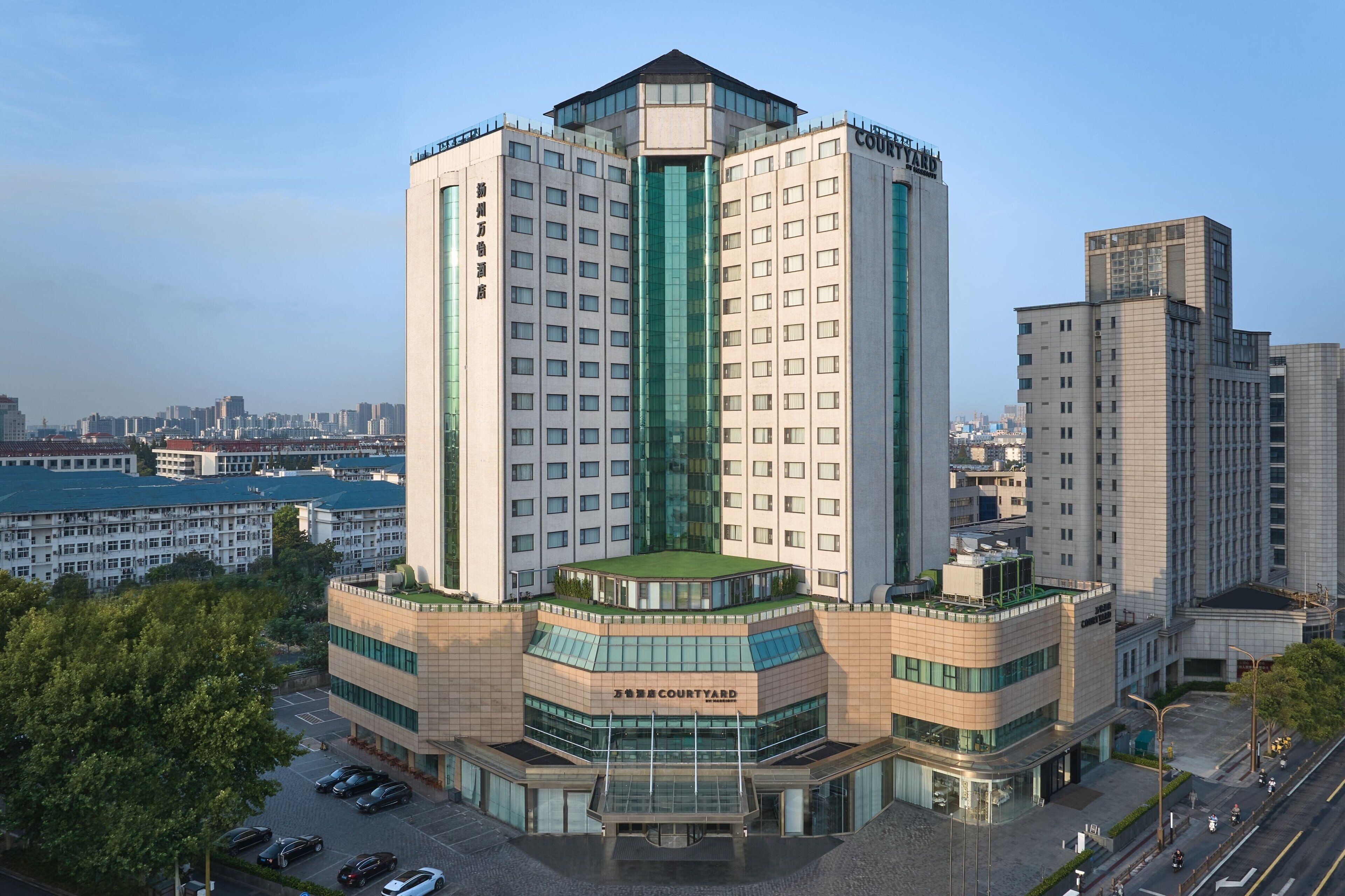 A multi-story hotel with a central courtyard, surrounded by other buildings.
