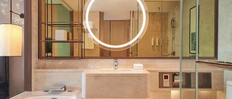 Un baño moderno con un espejo grande, una bañera, un inodoro y una zona de ducha con mampara de vidrio.