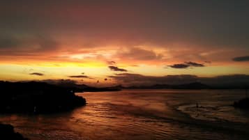 A sunset over a coastal landscape with calm waters reflecting the sky.