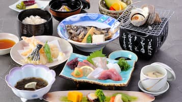 Variedad de platos japoneses, como sushi, sashimi y tempura, servidos en distintos platos y tazones.