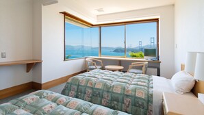A hotel room with a large window offering a view of a bridge and the sea. There is a bed with a quilted cover, a small table, and a chair. - Daichoso (Imabari)