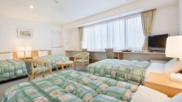 Camera d'albergo con due letti, una scrivania, una TV e una finestra con tende.