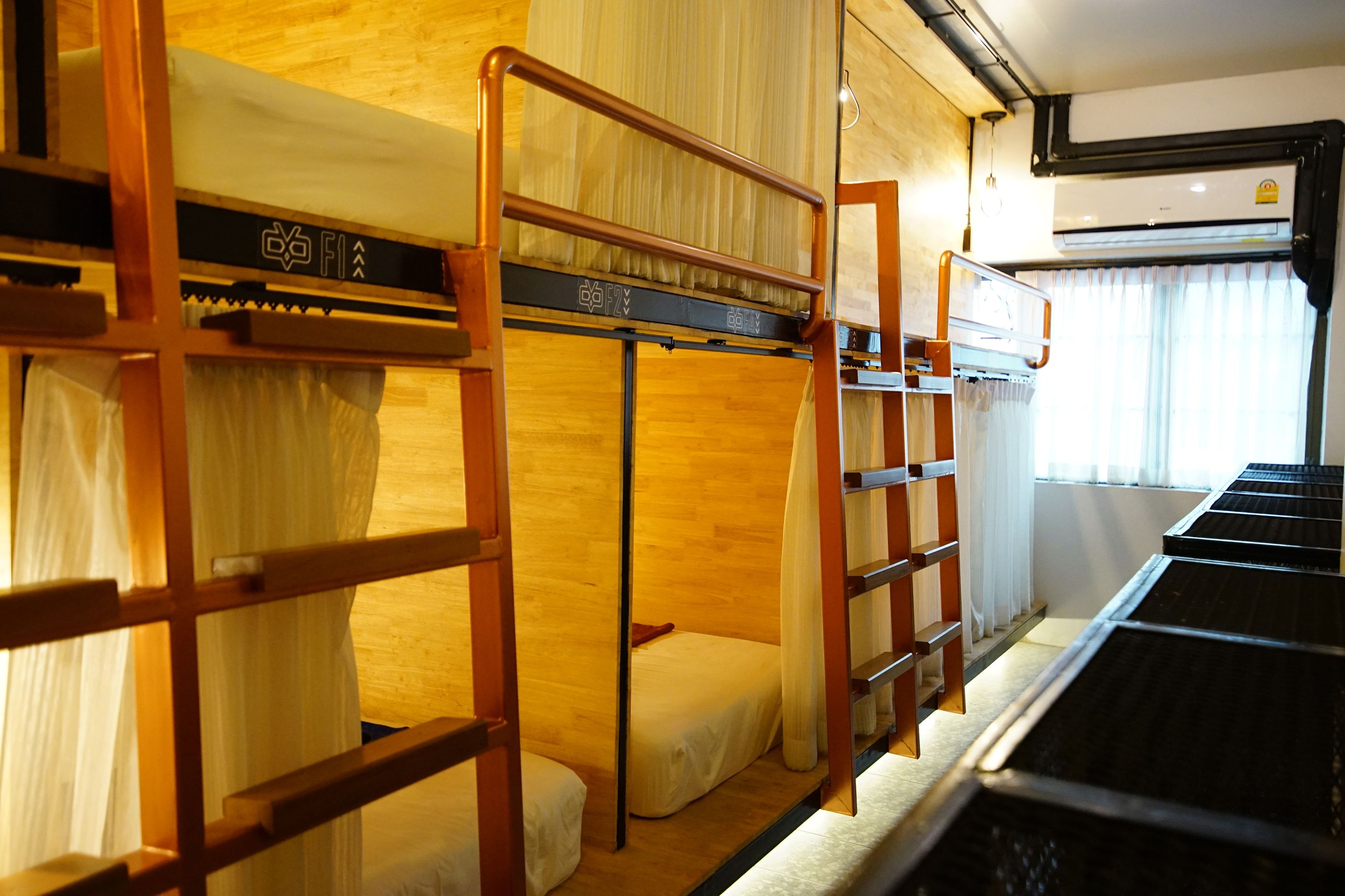 Ein Schlafzimmer mit Etagenbetten, Holzbalken und einem Fenster mit Vorhängen.