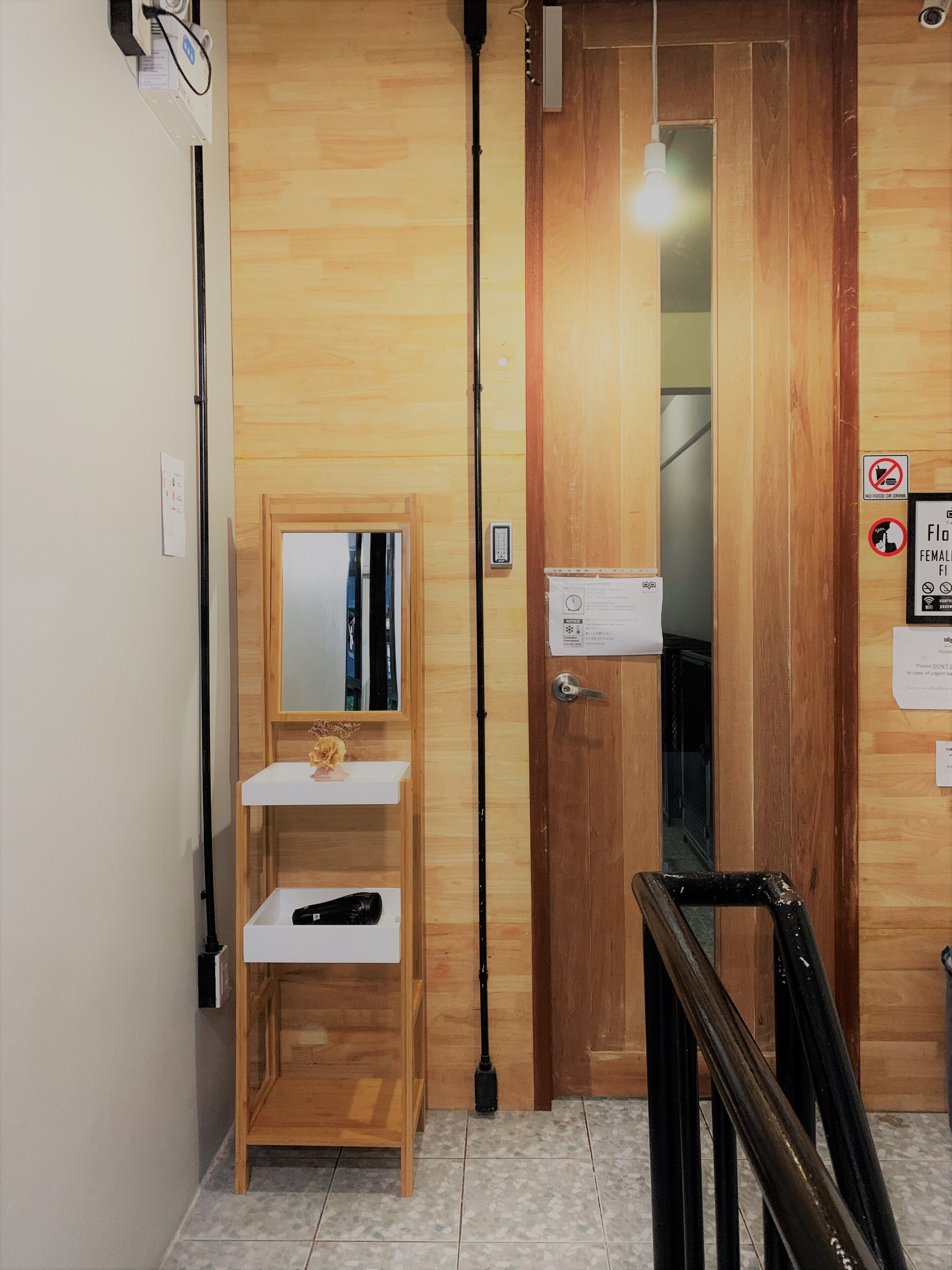A wooden interior with a small desk, a mirror, a door with a sign, and a light fixture.