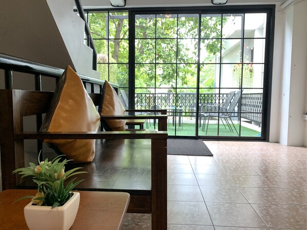 A seating area with a view of a balcony and outdoor greenery.
