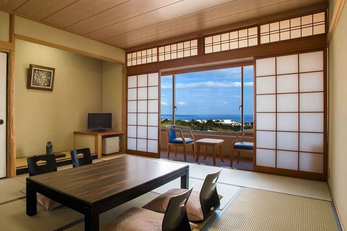 Una camera tradizionale in stile giapponese, con pavimento in tatami, un tavolino e sedie.