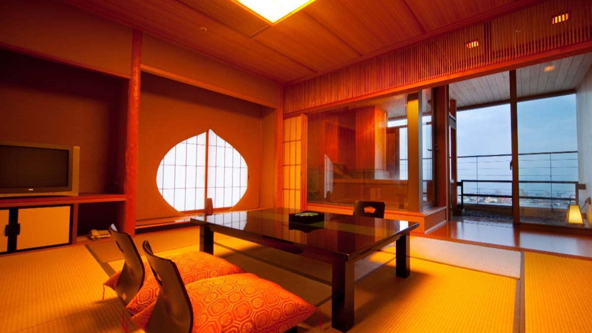 A traditional Japanese-style room with tatami flooring, a low table, and a television.