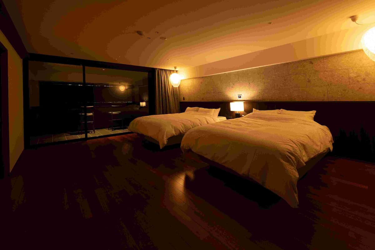 A hotel room with two beds, a large mirror, and a view of the cityscape.