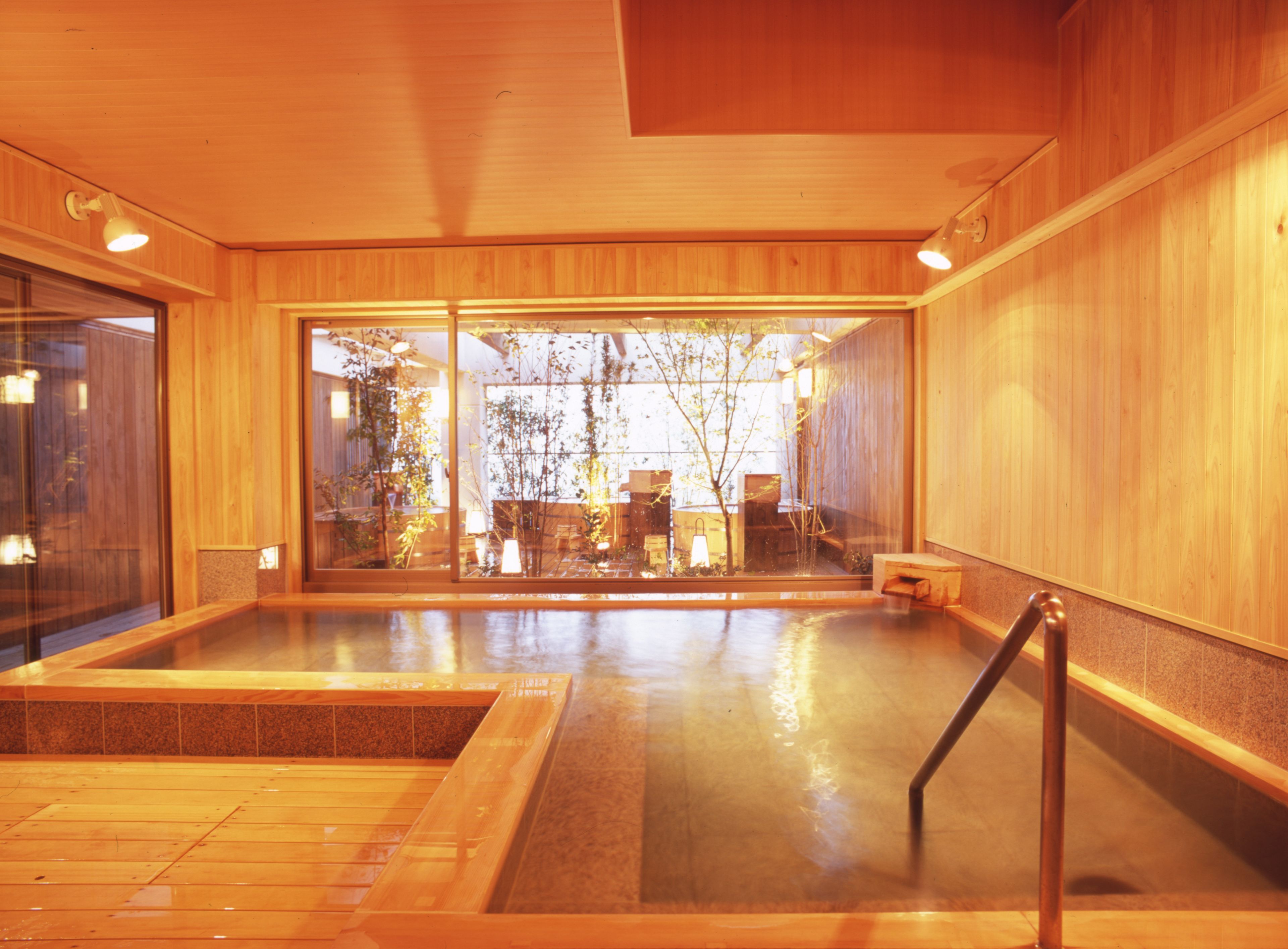 Un spa de madera con un jacuzzi, una terraza de madera y vistas a árboles.