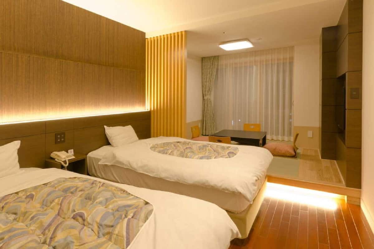 A hotel room with two beds, a desk, a chair, a phone, and a mirror.