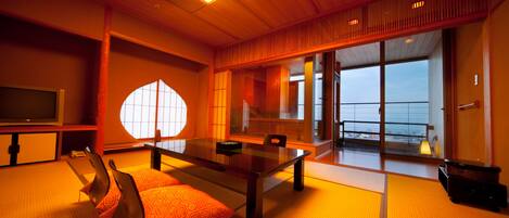 A traditional Japanese-style room with tatami flooring, a low table, and a sliding door leading to a balcony.