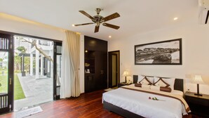 Un dormitorio amplio con una cama grande, un ventilador de techo, una mesita de noche y un cuadro enmarcado en la pared.
