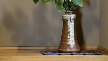 A vase with a plant on a wooden surface against a wall.