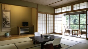 Ein traditioneller japanischer Raum mit Tatami-Boden, einem niedrigen Tisch und Schiebetüren.