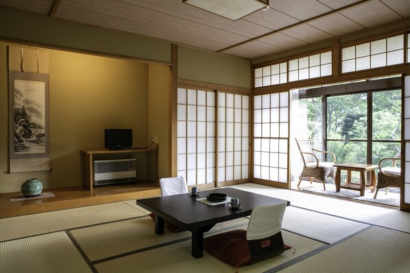 A traditional Japanese room with tatami flooring, a low table, and sliding doors. - Ryokan Warabino (Takayama)