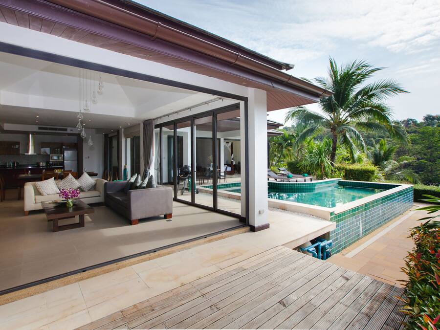 Una casa moderna con una amplia sala de estar, una piscina y vistas a palmeras.
