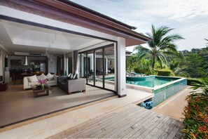 A modern house with a large open living area, a pool, and a view of palm trees. - Baan Phukhao (Krabi)