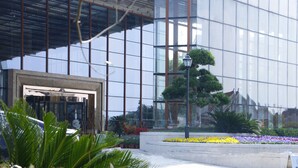 Un bâtiment moderne doté de grandes fenêtres en verre et d’un jardin bien entretenu, agrémenté de diverses plantes et fleurs.