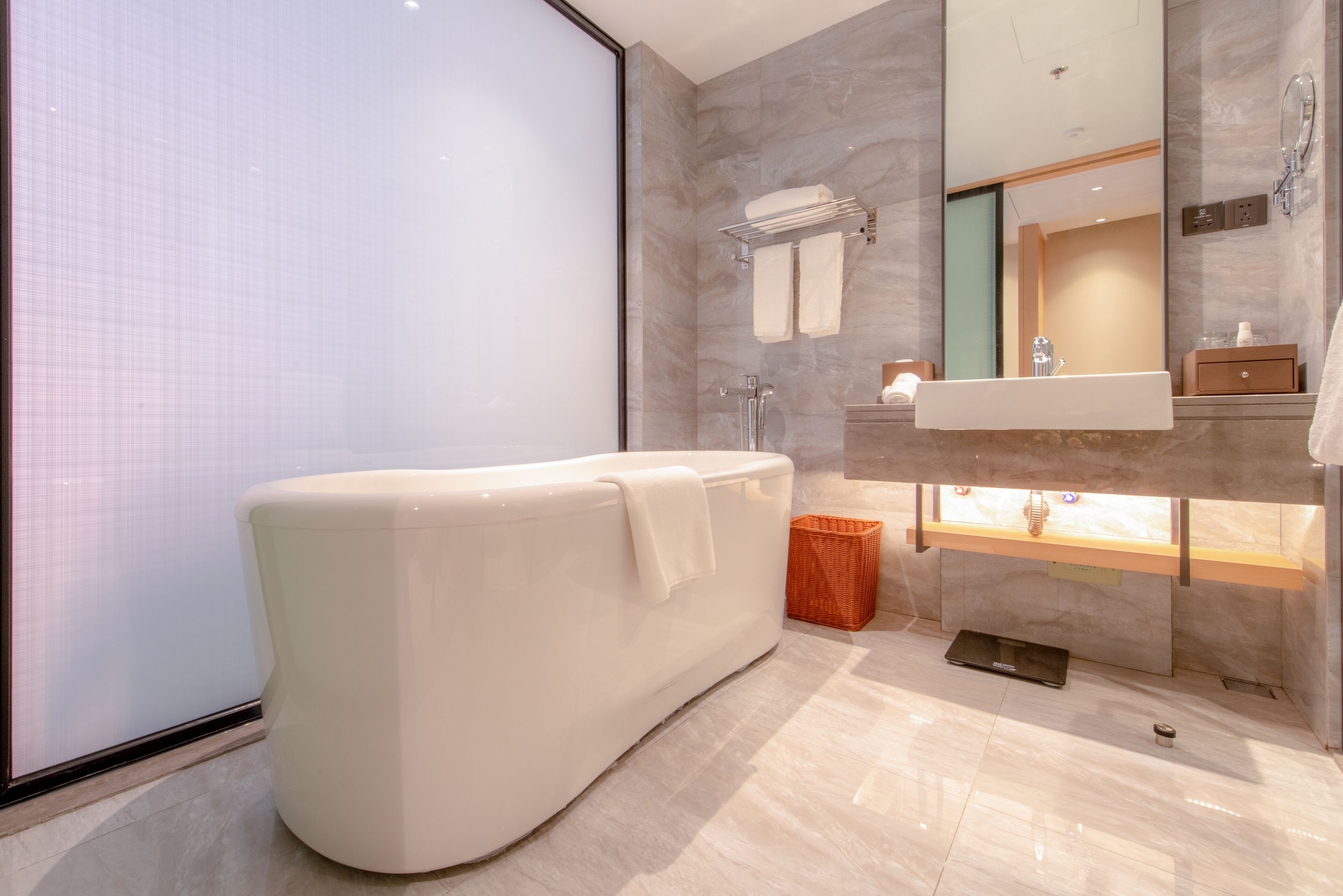 A modern bathroom with a freestanding bathtub, a vanity with a mirror, and a shower area.