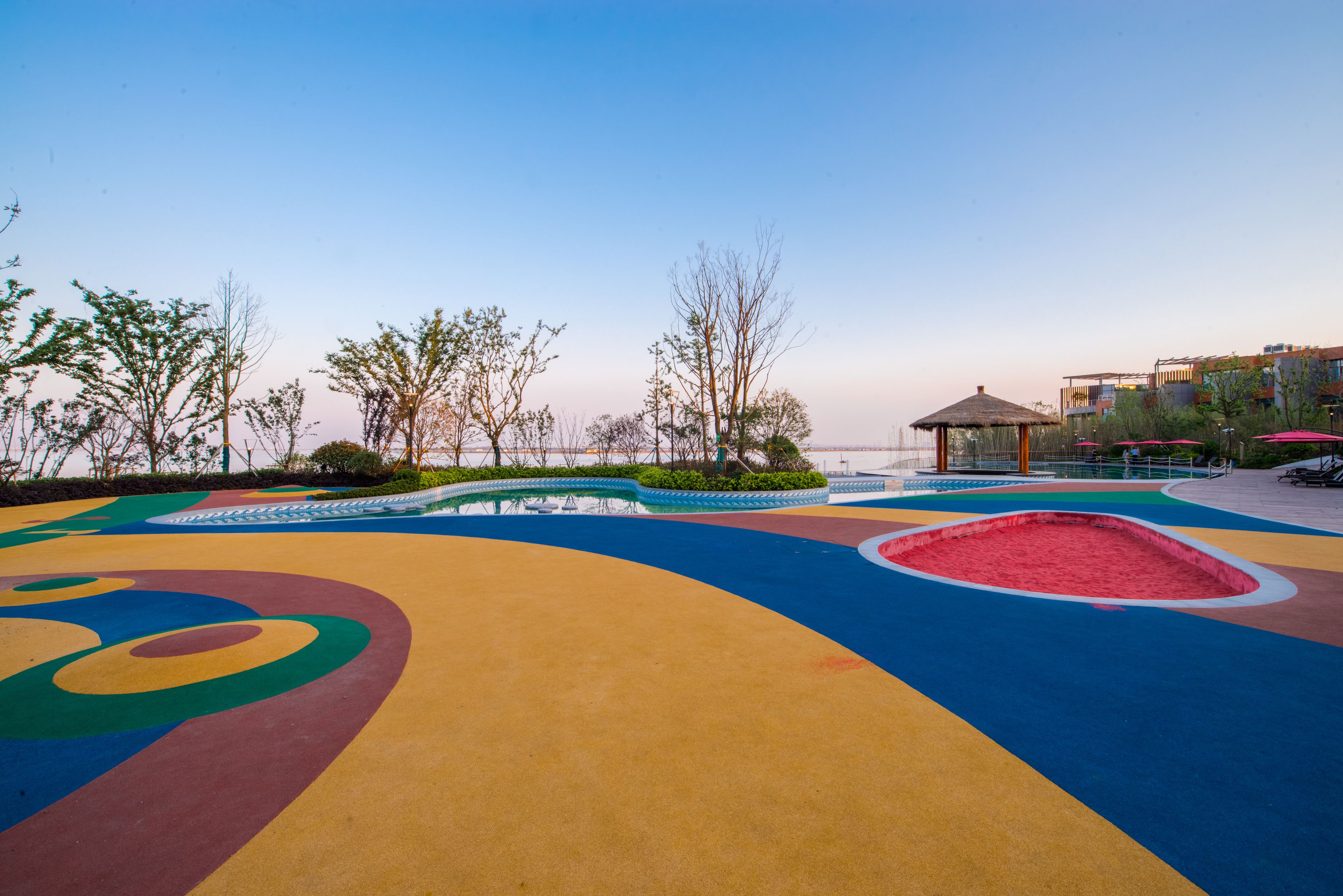 A colorful playground with a sandpit and a gazebo.