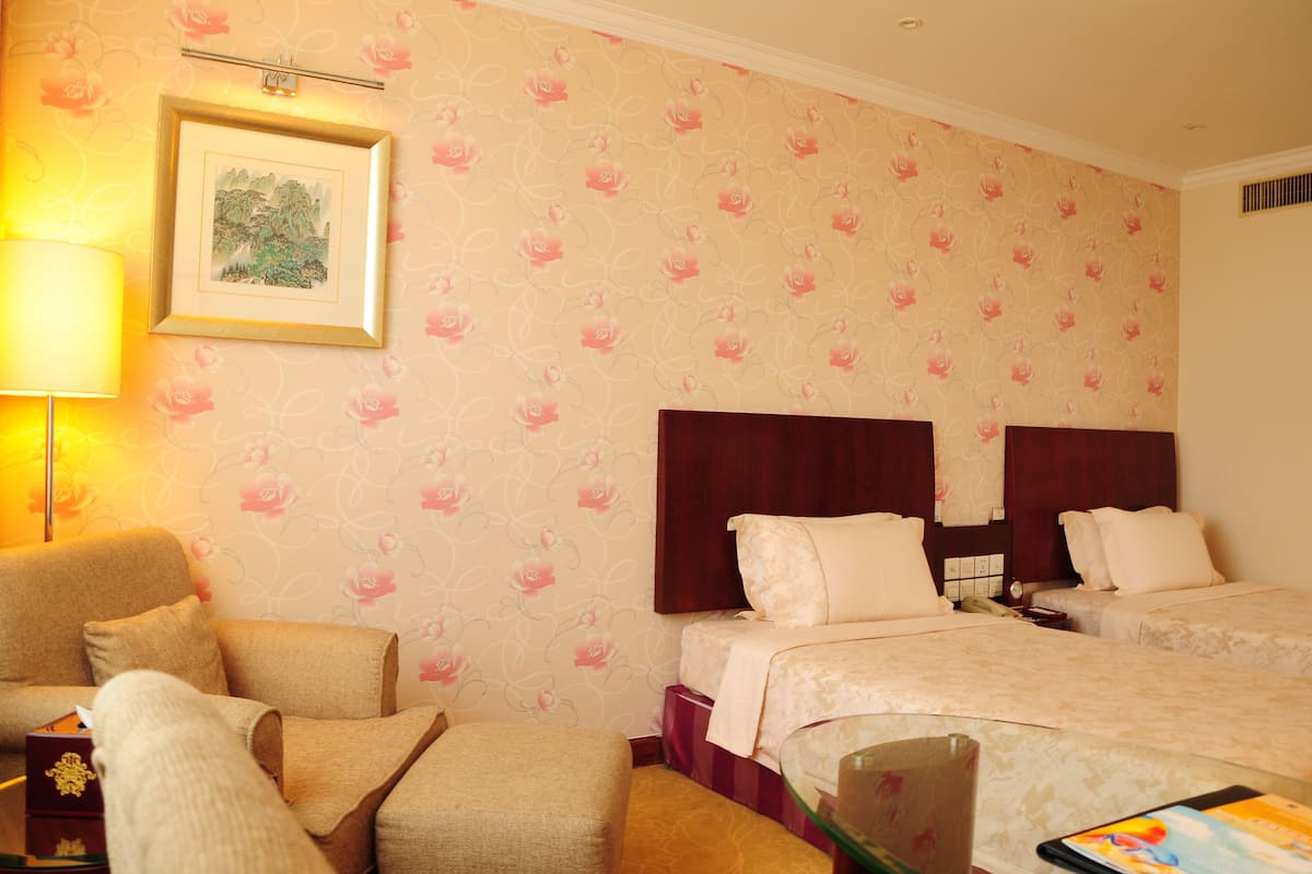 Een hotelkamer met twee bedden, een bank, een bureau en een lamp.