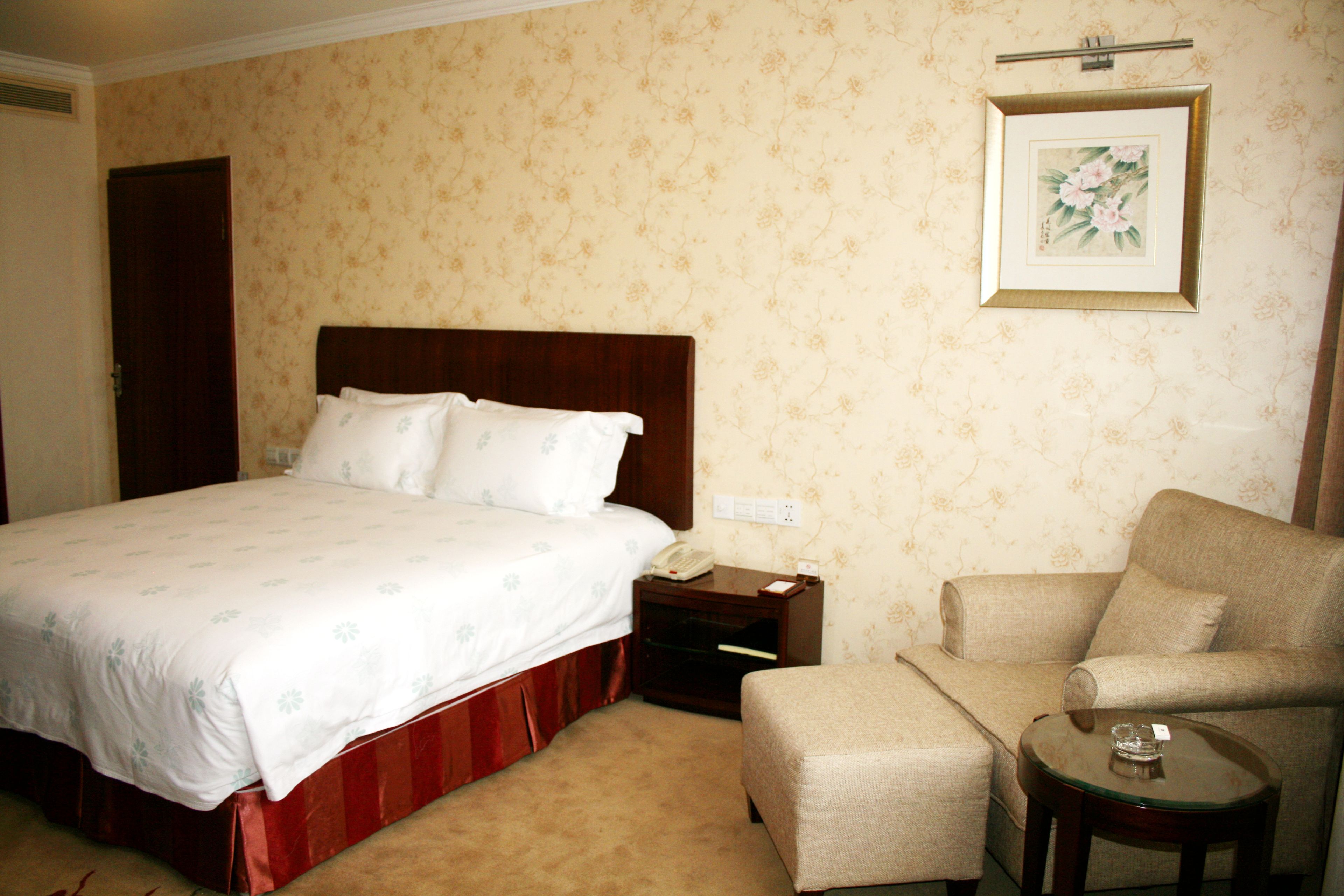 Une chambre d’hôtel avec un grand lit, une table de chevet, une chaise et une petite table.