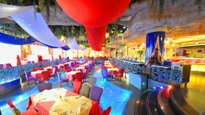 A restaurant with tables and chairs arranged in rows, a bar area, and a decorative ceiling.