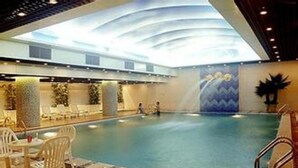 An indoor swimming pool with lounge chairs and a high ceiling with a skylight.