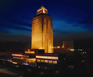 A tall hotel with multiple floors and a prominent tower section, surrounded by other buildings.