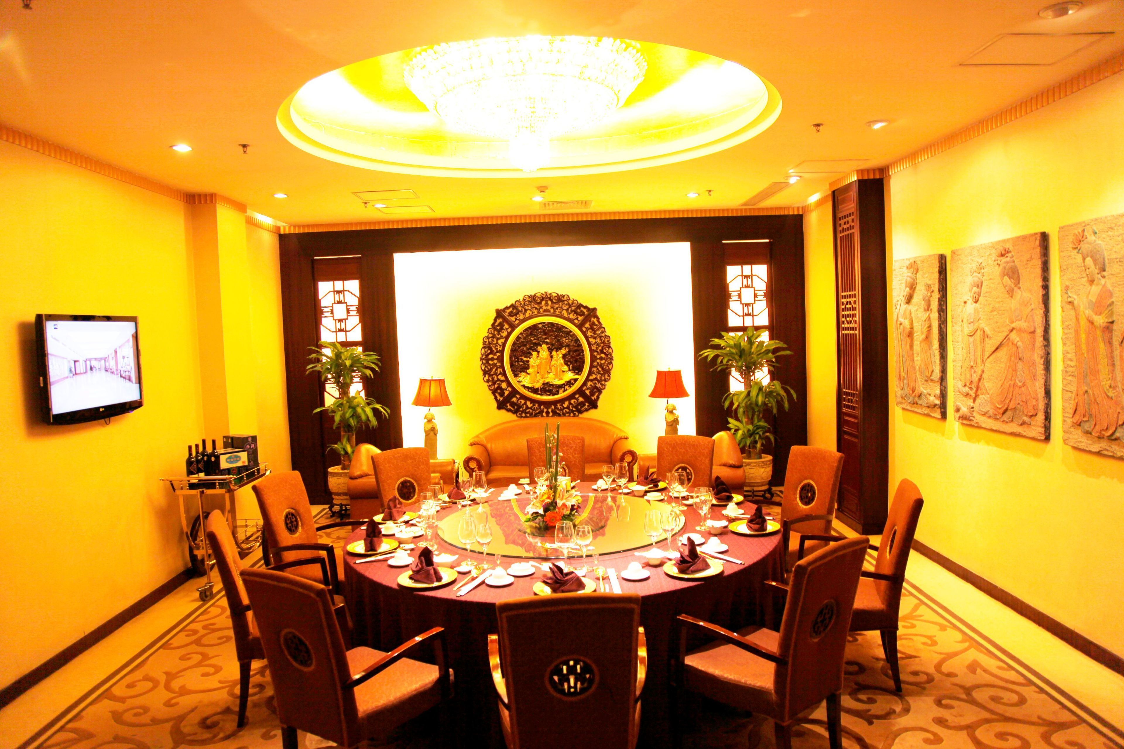 A conference room with a round table, chairs, and a chandelier.