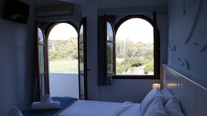 A bedroom with a bed, two windows, and a view of greenery outside. - Naiades Almiros River Hotel (Agios Nikolaos)