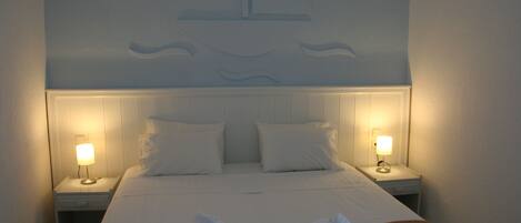 A hotel room with a bed, two bedside lamps, and a headboard with a wave design.