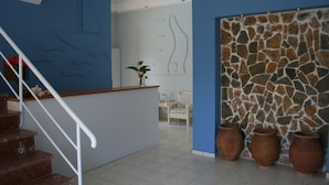 A staircase leading to a reception area with a blue wall, a stone wall, and three large pots. - Naiades Almiros River Hotel (Agios Nikolaos)