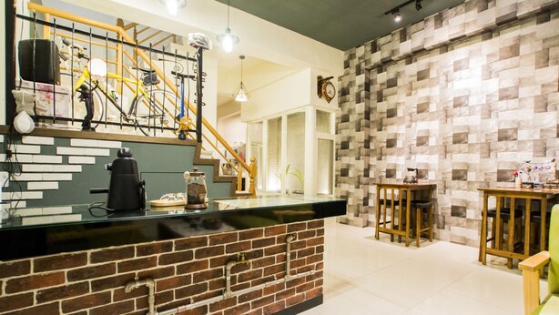 Un área de bar moderna con mostrador de ladrillo, una escalera y pared de cuadros.