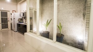 Una cocina moderna con electrodomésticos blancos, una ventana con vistas a una pared texturizada y plantas en macetas.