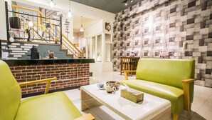 Un interior moderno con una pared de ladrillo decorativa, una escalera y un área de estar con un sofá verde y sillas de madera.