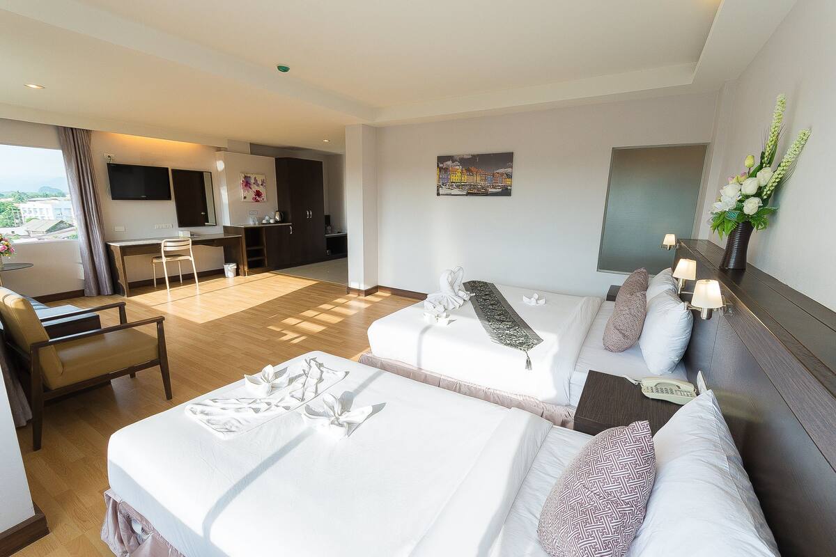 Habitación de hotel con dos camas, un escritorio, una silla, un televisor y un cuadro en la pared.