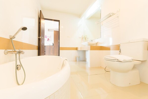 A modern bathroom with a bathtub, toilet, and sink. - Sinkiat Buri Hotel (Satun)