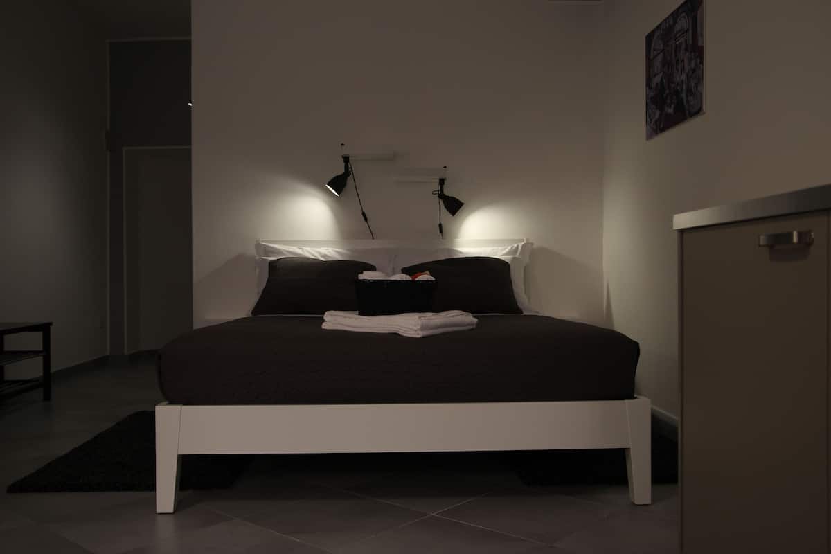 Una camera da letto moderna con un letto a cornice bianca, biancheria da letto scura e due abat-jour.