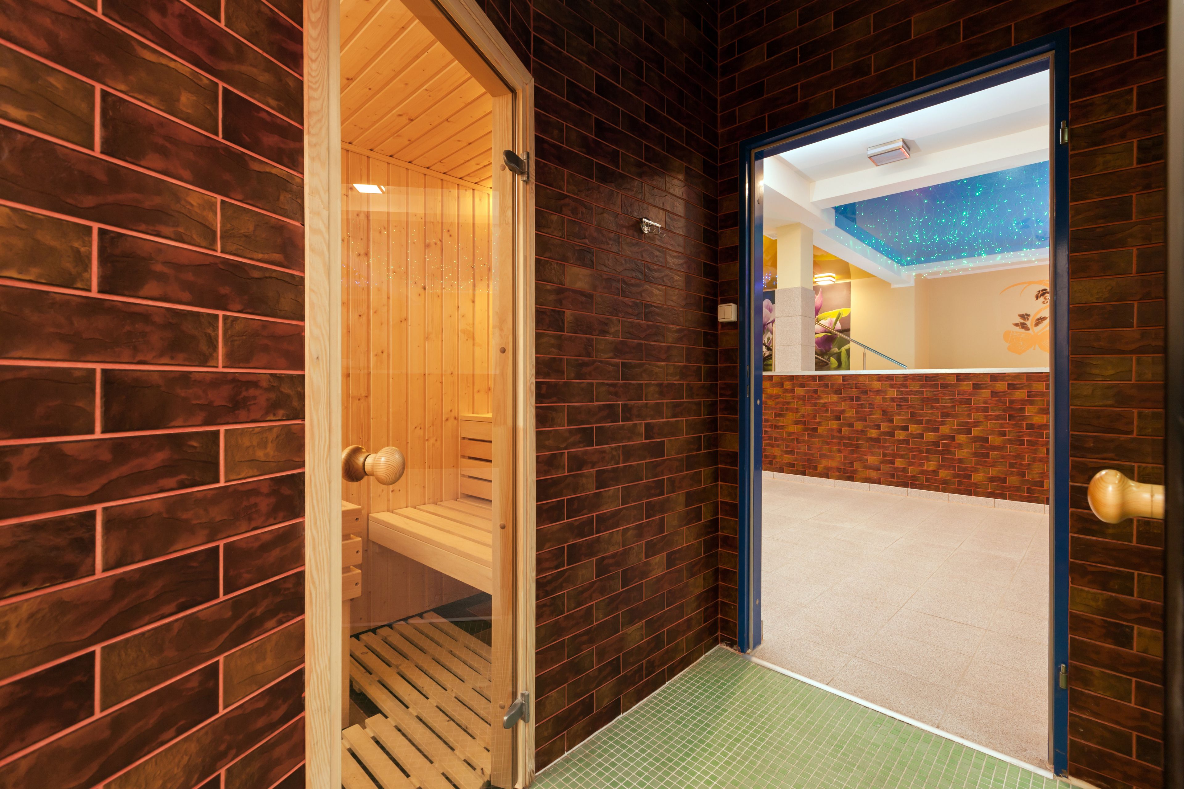 A wooden sauna with a sloped ceiling, a tiled floor, and a wooden bench.