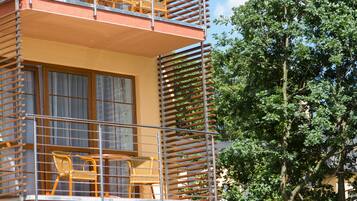 A multi-story building with balconies, each featuring metal railings and wicker chairs.