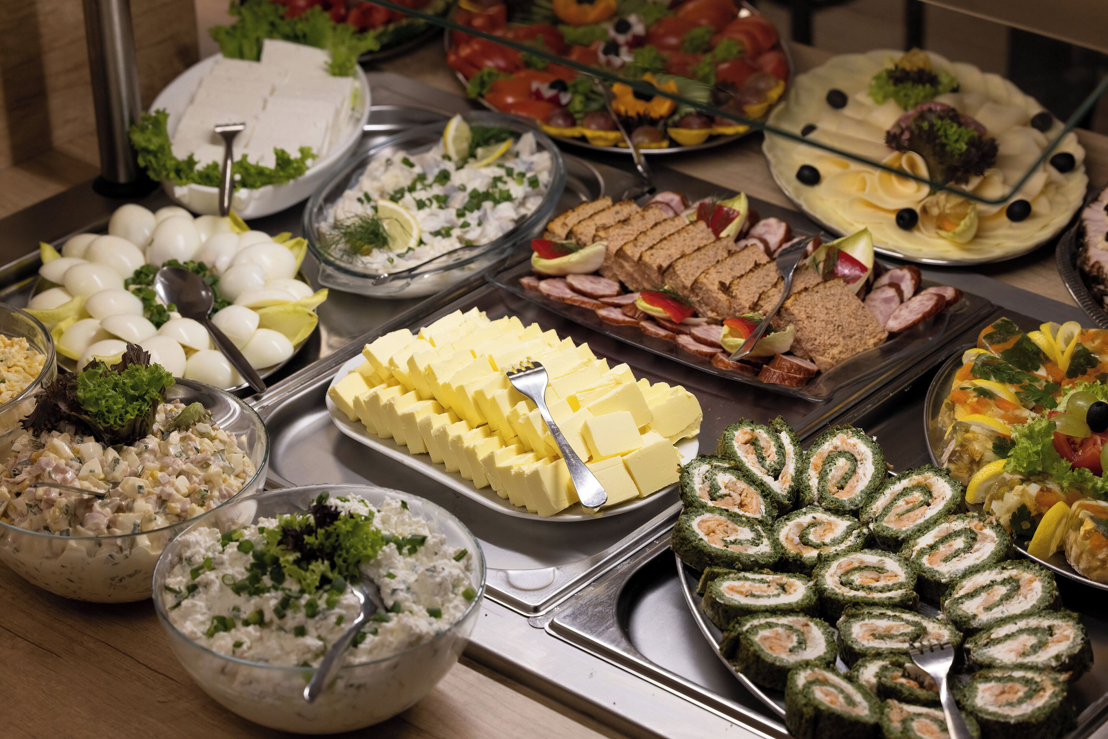 Un bufé con diversos alimentos, como huevos, queso y rollos de sushi.