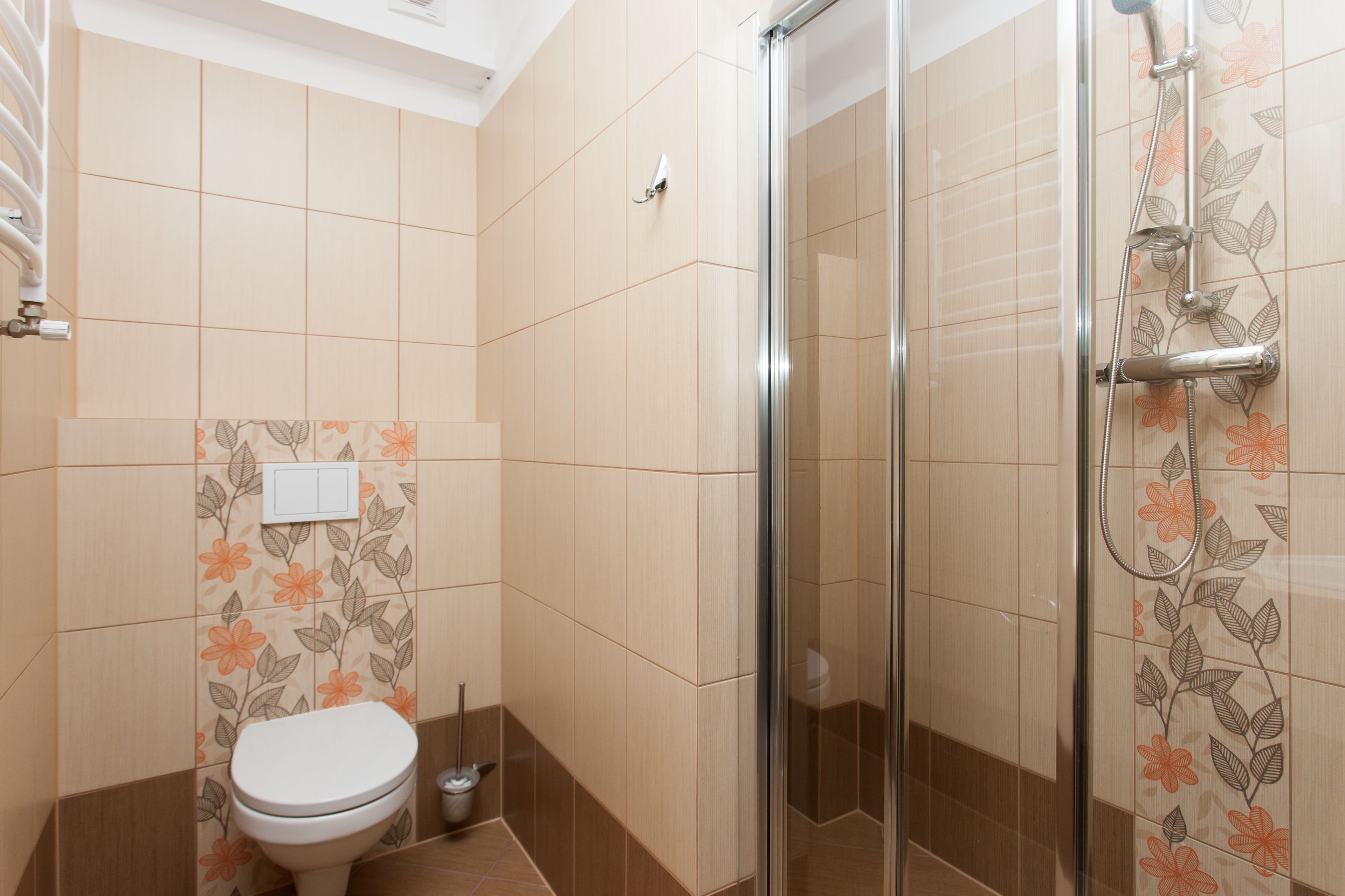 A bathroom with a toilet, shower, and tiled walls.