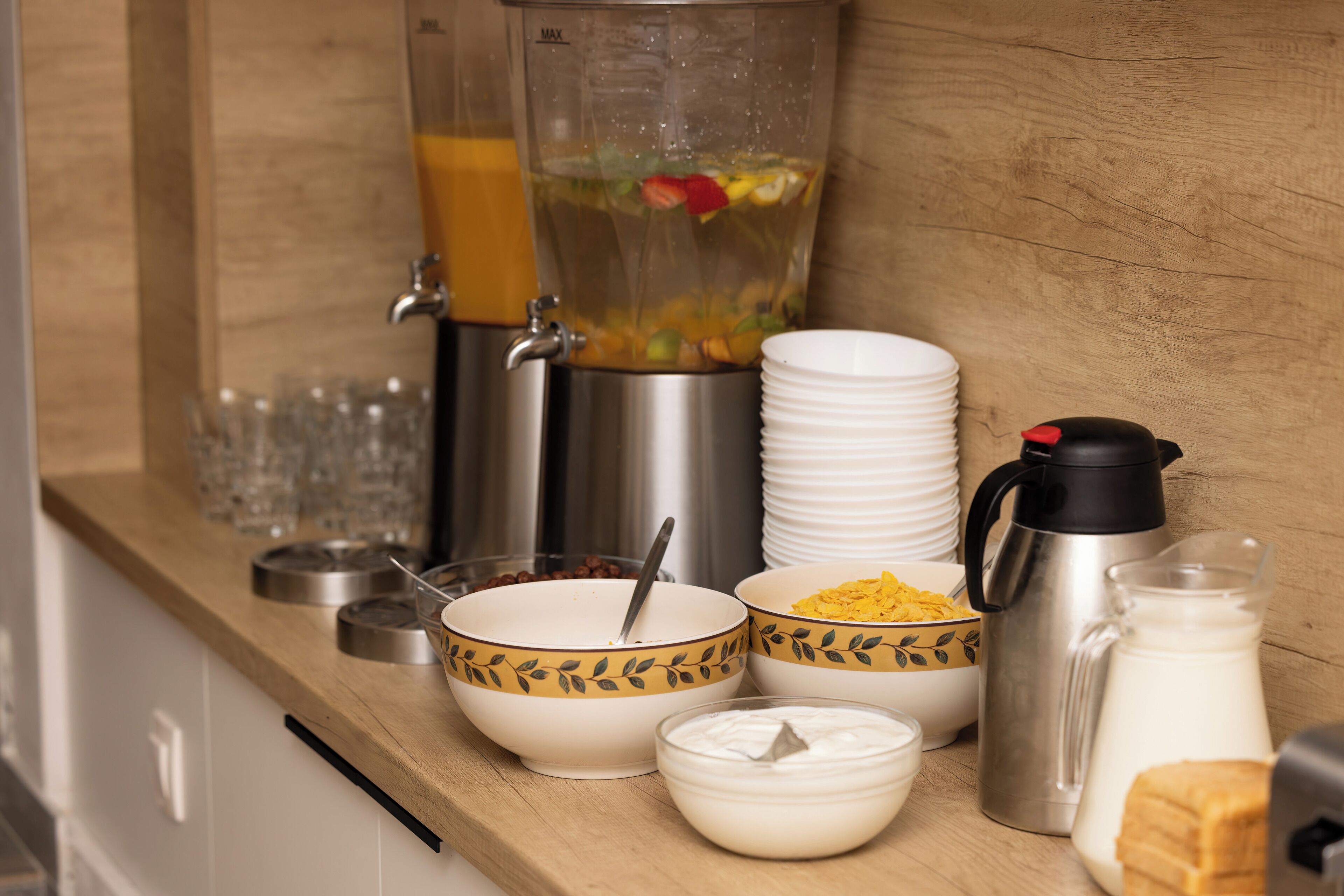 A breakfast buffet setup with various food items and drink dispensers.