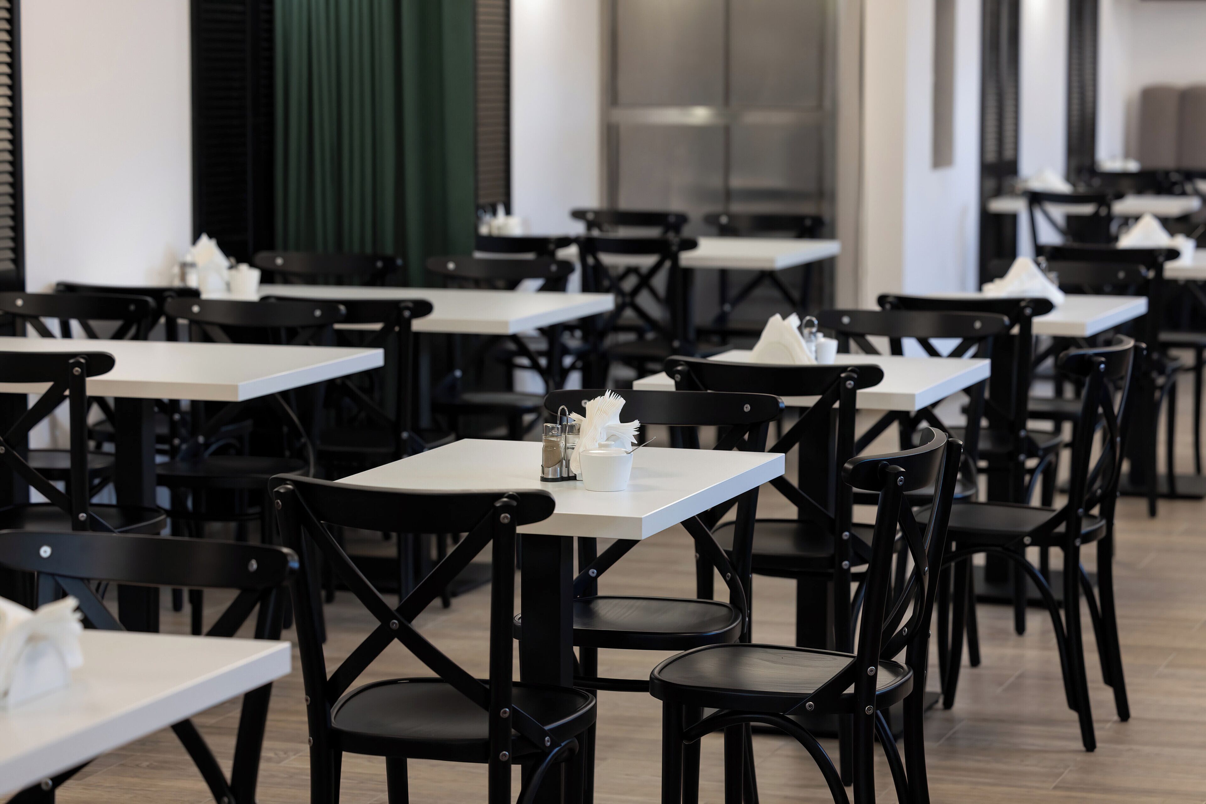 A restaurant with multiple tables and chairs, arranged in rows.