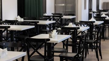 A restaurant with multiple tables and chairs, arranged in rows.